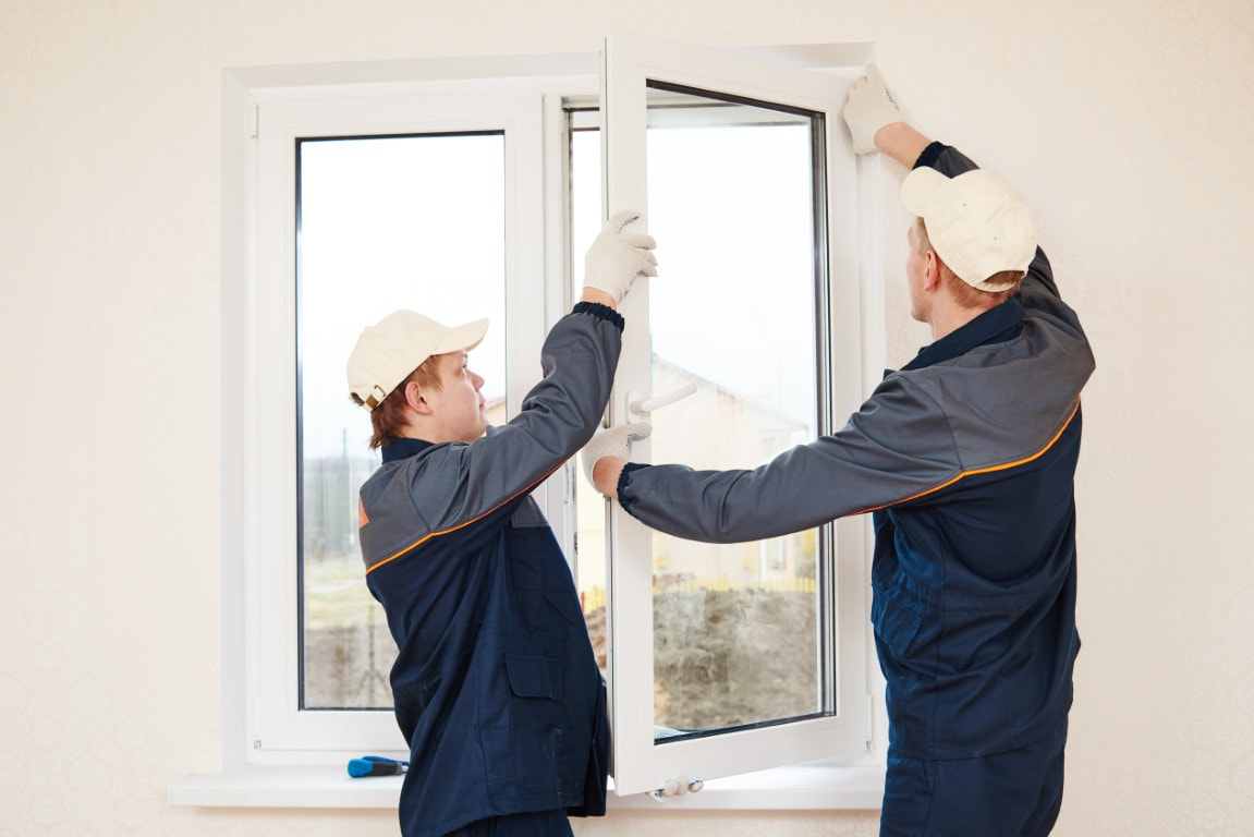 An image of two men replacing a glass window with a hurricane proof glass window